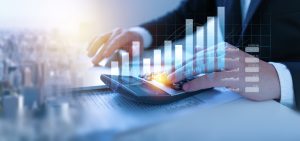 Persona che utilizza una calcolatrice con grafici finanziari in sovrimpressione