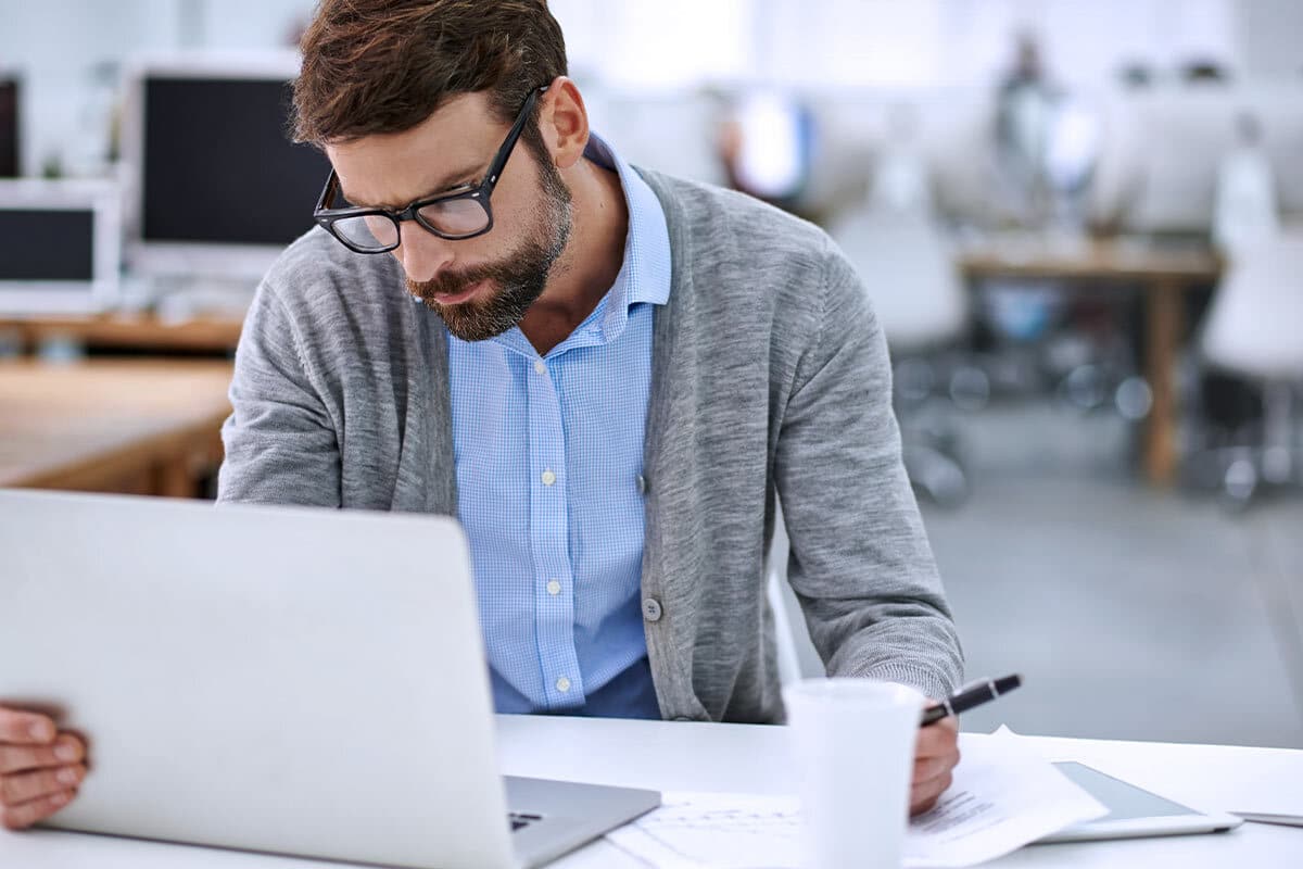 Un uomo che lavora al computer con un'espressione concentrata, riflettendo sulla questione dell'imposta di bollo sul fondo pensione