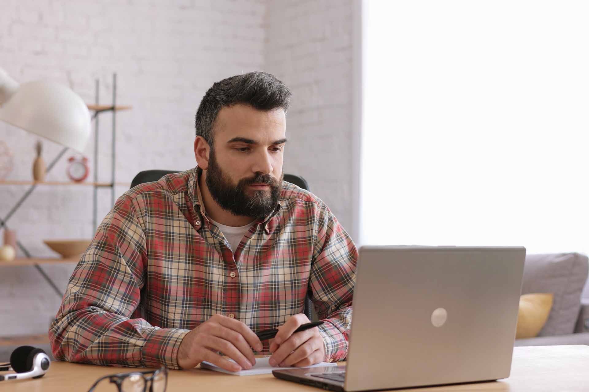 Uomo adulto che lavora al computer, riflettendo sul processo per effettuare il cambio di comparto nel Fondo Telemaco.