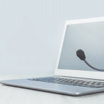 Laptop con cuffie e microfono poggiati sullo schermo, simbolo dell’assistenza telefonica e dei servizi di supporto agli utenti.
