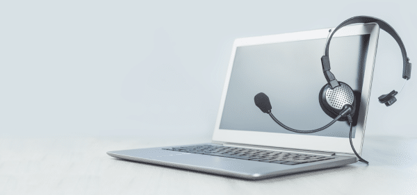 Laptop con cuffie e microfono poggiati sullo schermo, simbolo dell’assistenza telefonica e dei servizi di supporto agli utenti.