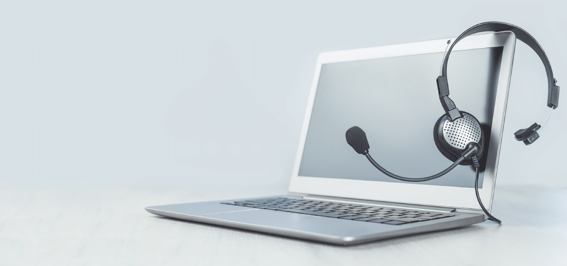 Laptop con cuffie e microfono poggiati sullo schermo, simbolo dell’assistenza telefonica e dei servizi di supporto agli utenti.
