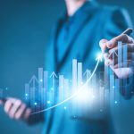 Un uomo traccia con una penna una linea ascendente su un grafico finanziario digitale e luminoso, simboleggiando la crescita economica e l'andamento positivo dei rendimenti.