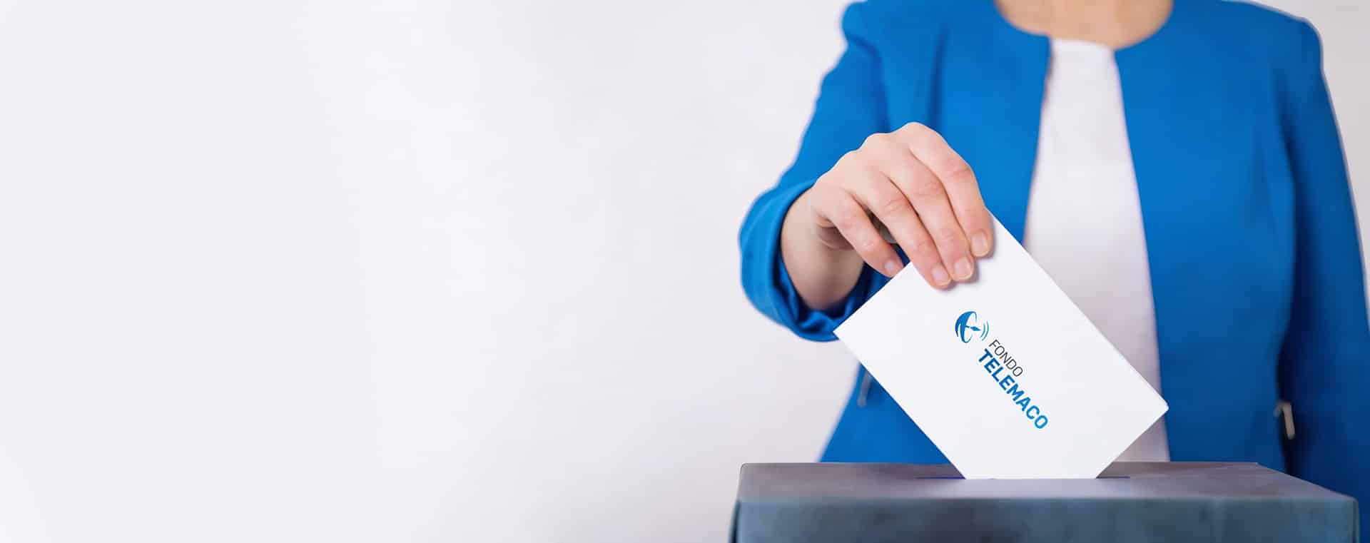 Una persona che indossa una giacca blu inserisce una busta bianca elettorale, riportante il logo del Fondo Telemaco, all'interno di un'urna.