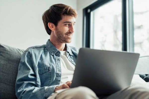 Un giovane lavoratore consulta con soddisfazione i dati sulla crescita dei fondi negoziali iscritti in aumento dal proprio laptop