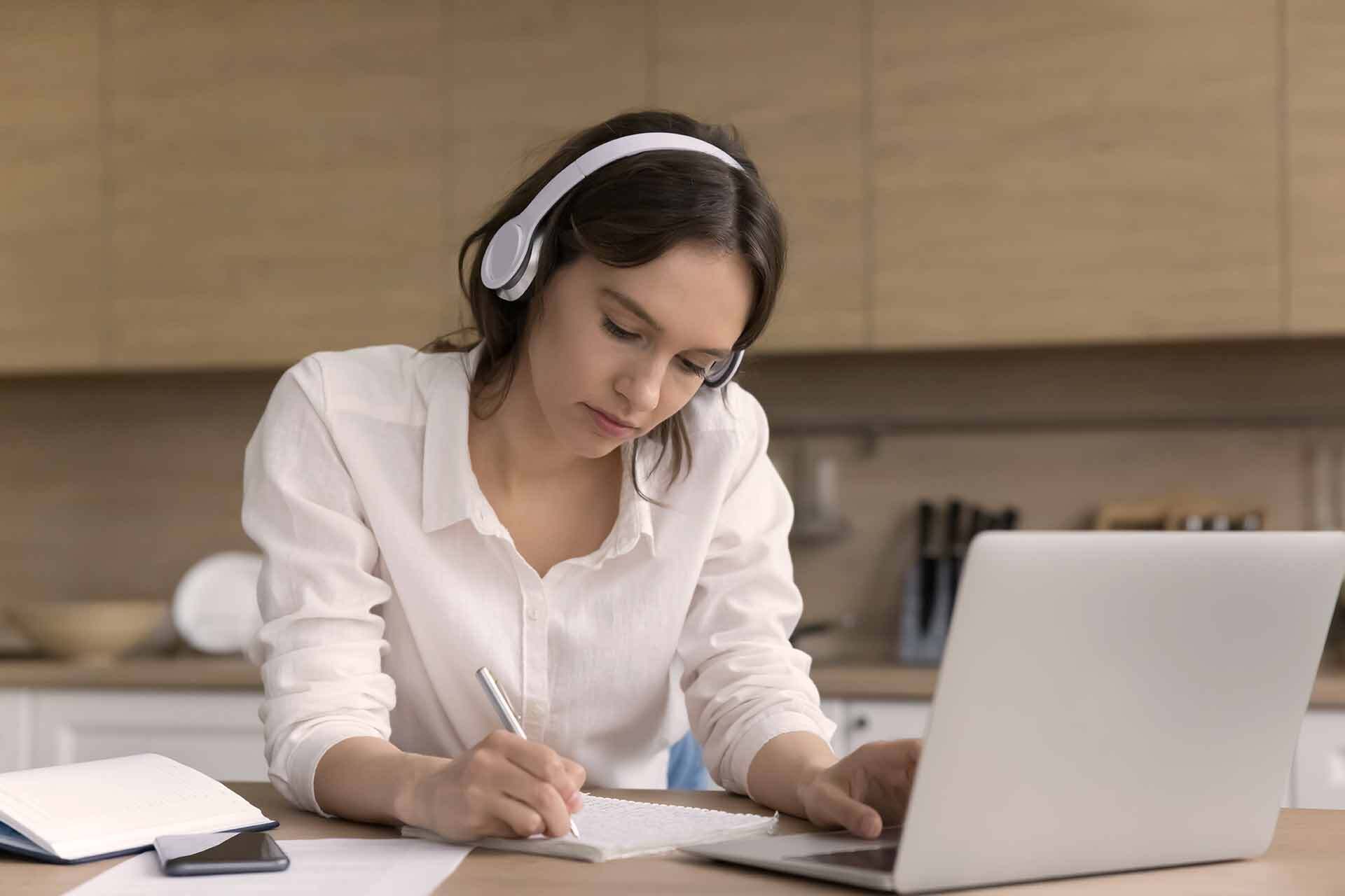 Una giovane donna studia al computer prendendo appunti, simbolo dell'educazione previdenziale come miglior investimento per la pensione.