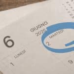 Calendario da tavolo cartaceo aperto sul mese di giugno 2026, con il giorno martedì 2 giugno cerchiato in blu per evidenziare la data.