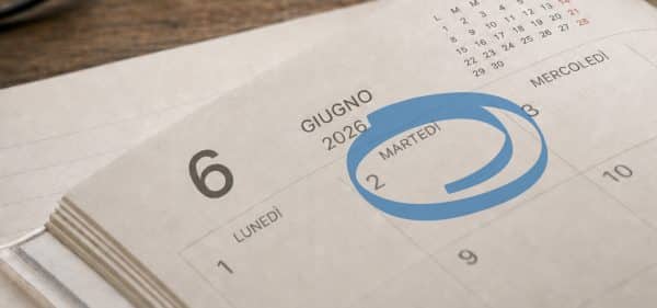 Calendario da tavolo cartaceo aperto sul mese di giugno 2026, con il giorno martedì 2 giugno cerchiato in blu per evidenziare la data.