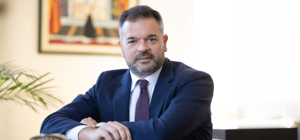 Foto ufficiale di Stefano Castrignanò, nuovo Presidente di Fondo Telemaco, seduto a una scrivania in un ufficio, con abito blu e cravatta bordeaux, mentre guarda verso l’obiettivo.