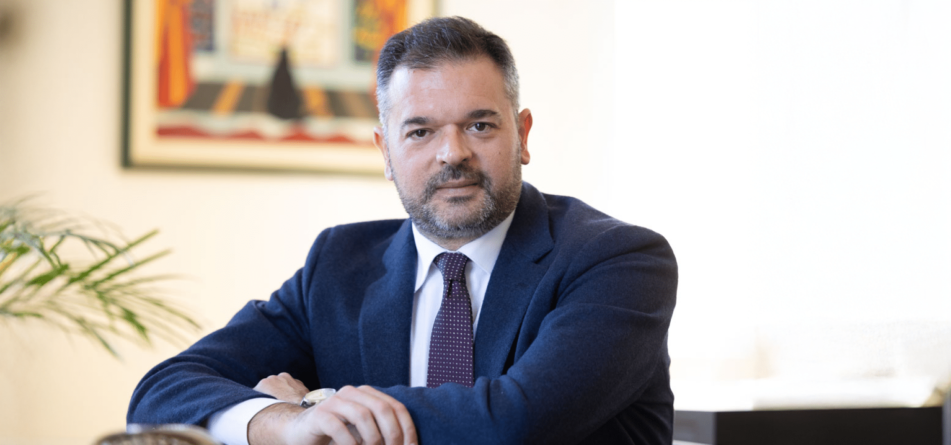 Foto ufficiale di Stefano Castrignanò, nuovo Presidente di Fondo Telemaco, seduto a una scrivania in un ufficio, con abito blu e cravatta bordeaux, mentre guarda verso l’obiettivo.