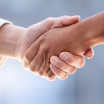 Stretta di mano ravvicinata tra due persone in abito professionale.