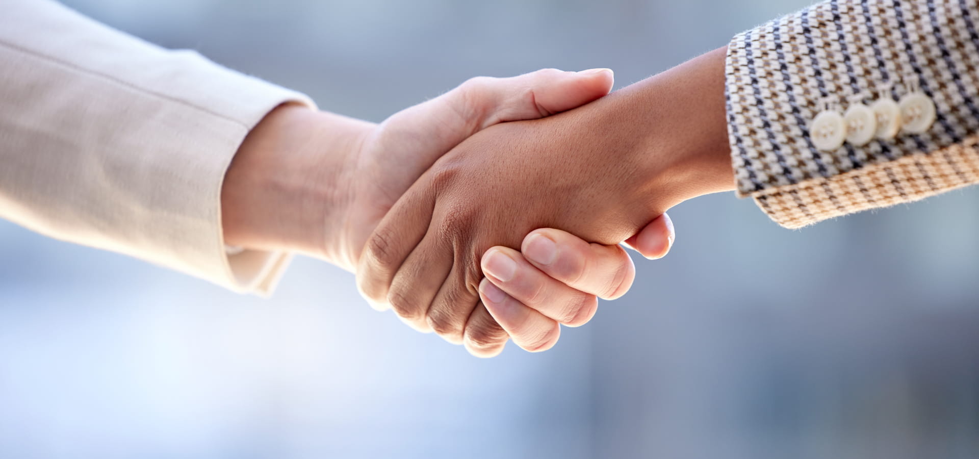 Stretta di mano ravvicinata tra due persone in abito professionale.
