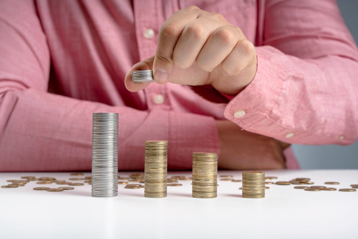 Persona dispone pile di monete di diversa altezza, immagine sul glide path e sulla riduzione progressiva del rischio pensionistico