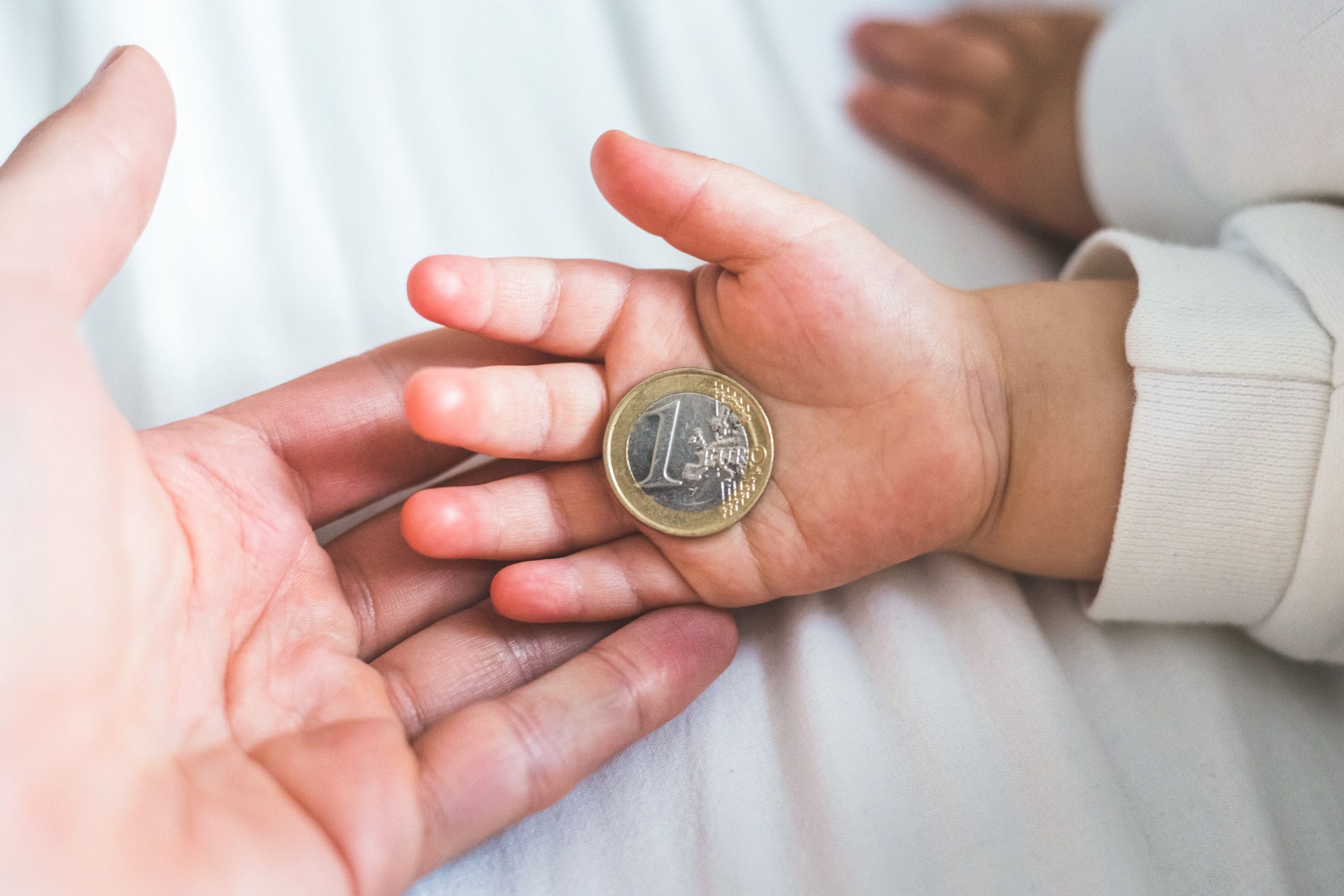 Mano di un neonato con una moneta da un euro, immagine sul tema del fondo previdenziale alla nascita